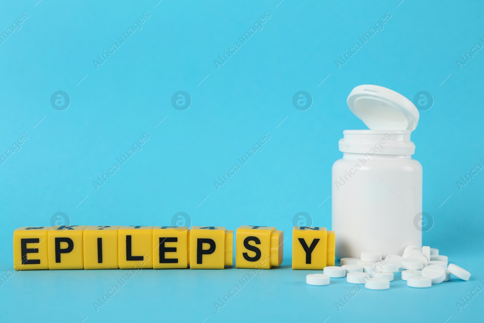 Photo of Blocks with word Epilepsy and pills on light blue background, space for text
