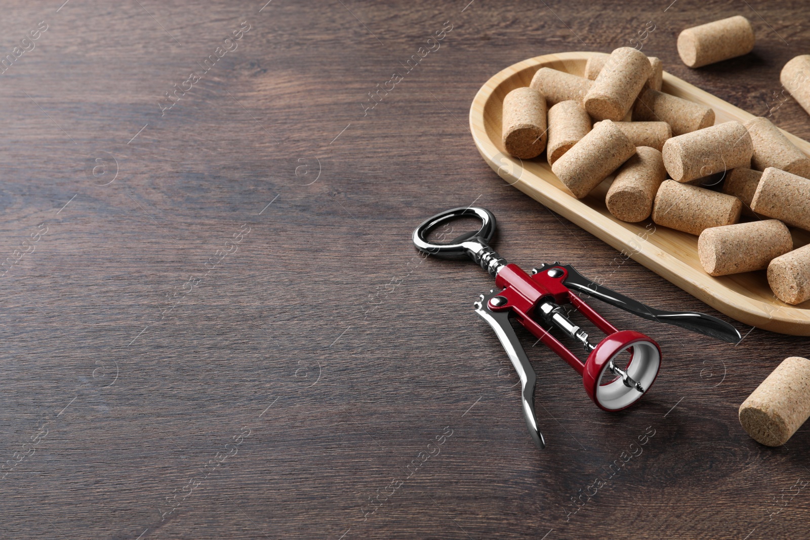 Photo of Corkscrew and wine bottle stoppers with plate on wooden table. Space for text