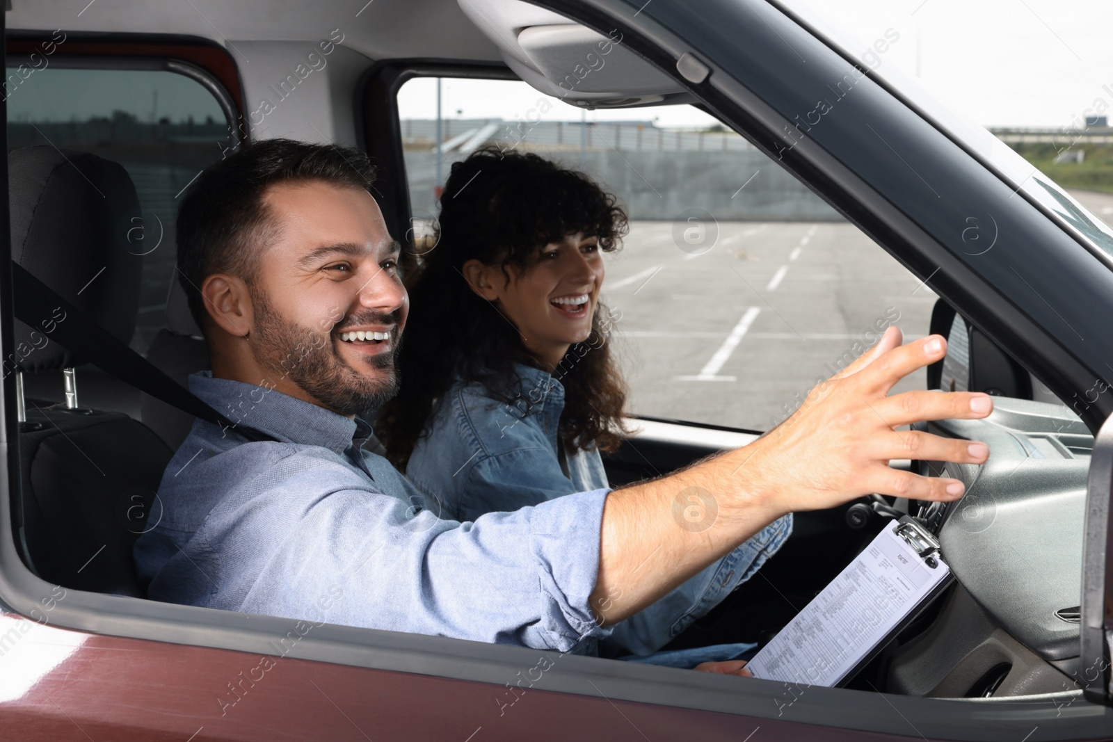 Photo of Driving school. Happy student passing driving test with examiner in car at parking lot