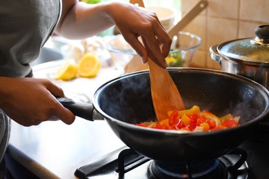 Photo of Woman cooking vegetables in frying pan indoors, closeup