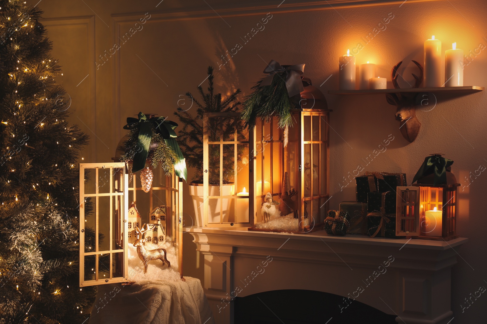 Photo of Beautiful wooden lanterns and other decorations on mantelpiece in room with Christmas tree