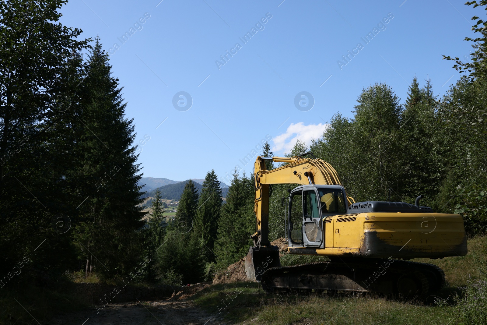 Photo of Crawler excavator near dirt road in forest