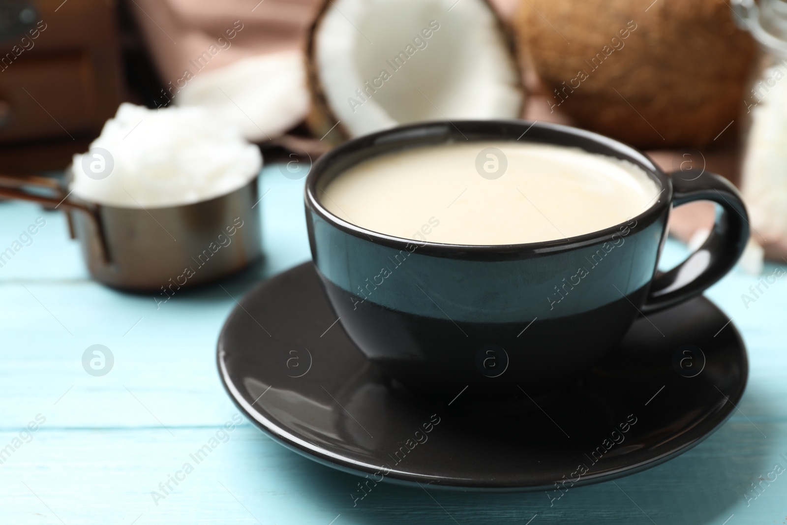 Photo of Delicious coffee with organic coconut oil on blue wooden table