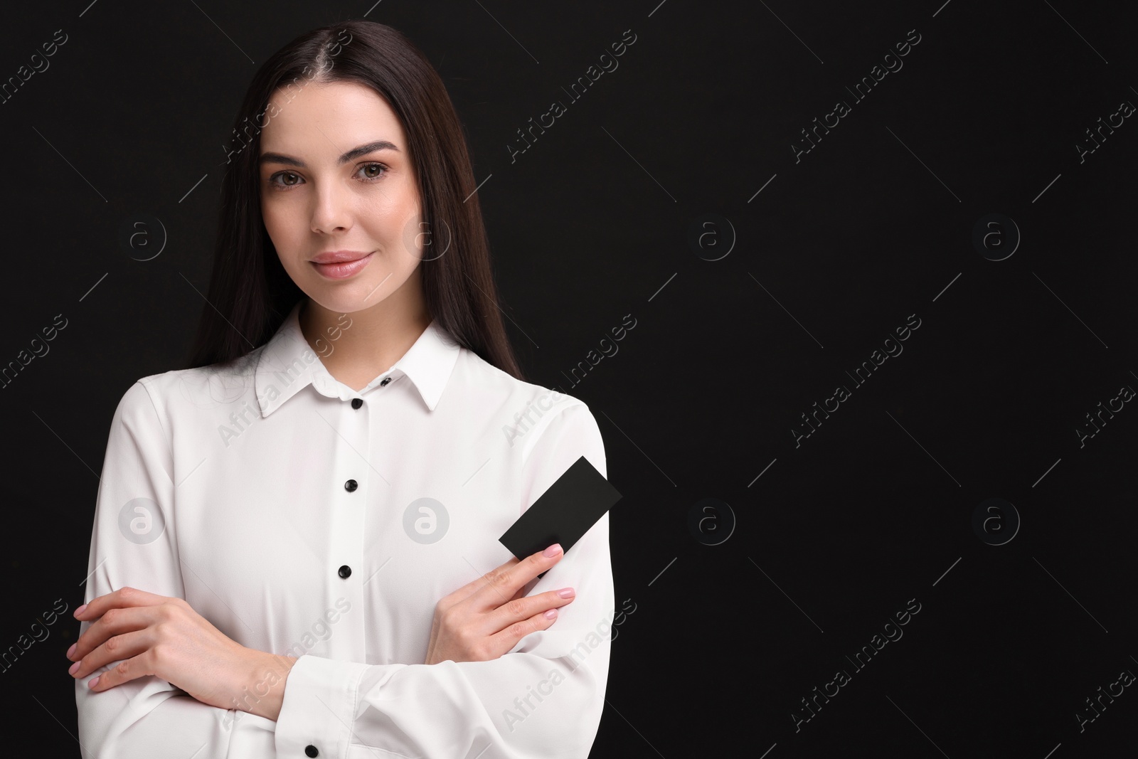 Photo of Woman holding blank business card on black background. Space for text