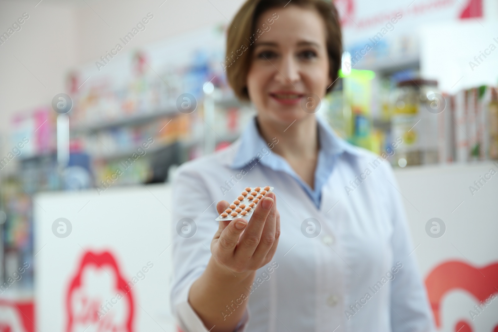 Photo of Professional pharmacist in drugstore, focus on hand with pills