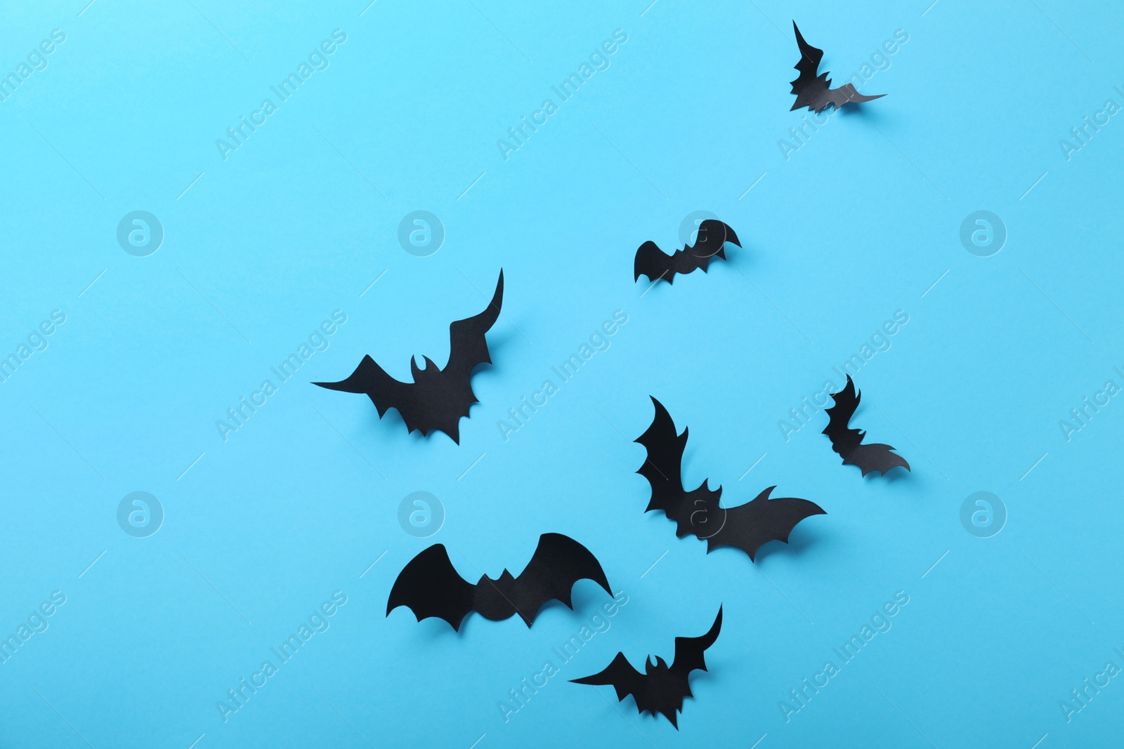 Photo of Paper bats on light blue background, flat lay. Halloween decor