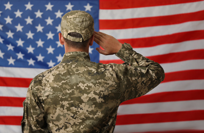 Photo of Male soldier in uniform against USA flag, back view