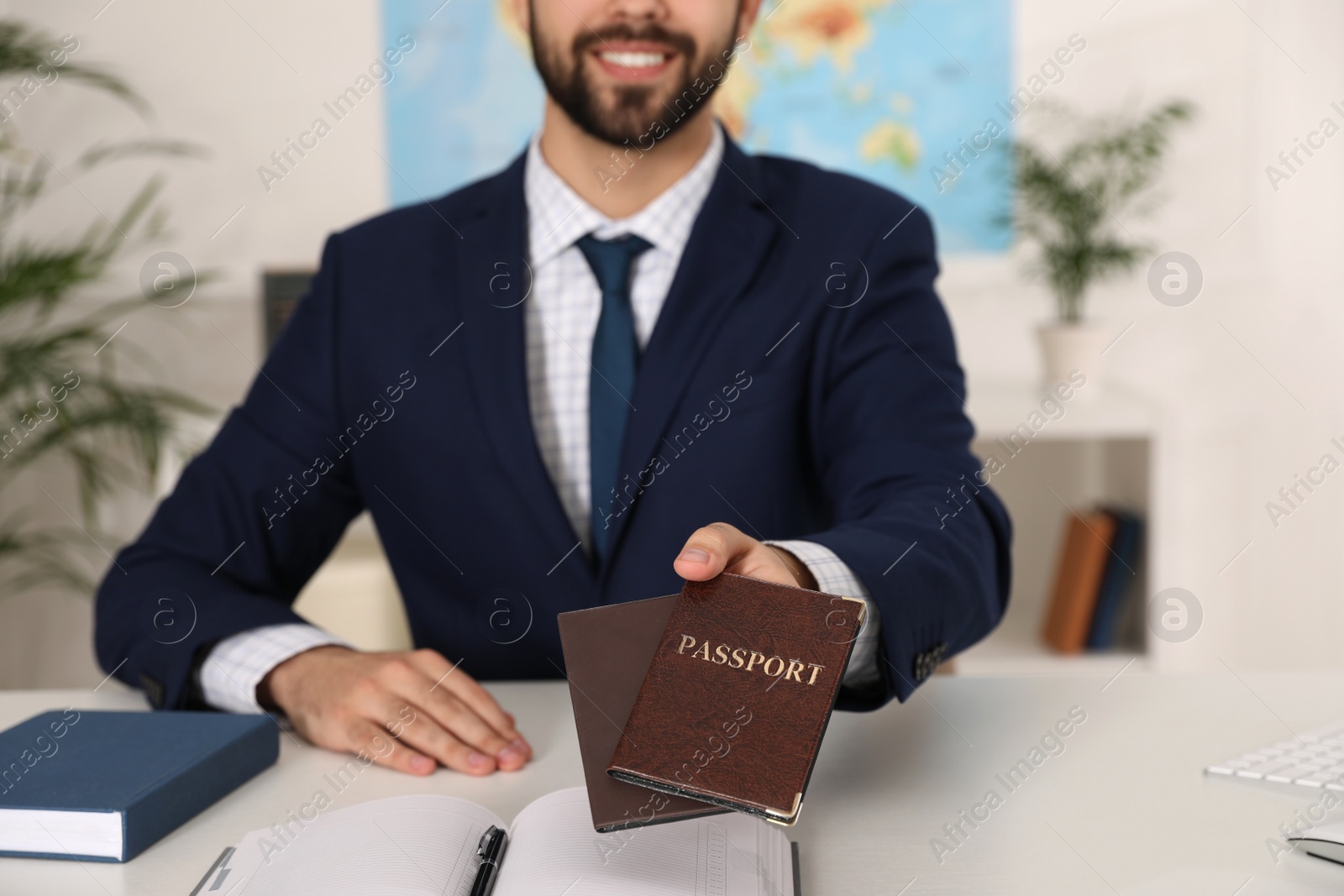 Photo of Happy manager holding passports at desk in travel agency, closeup