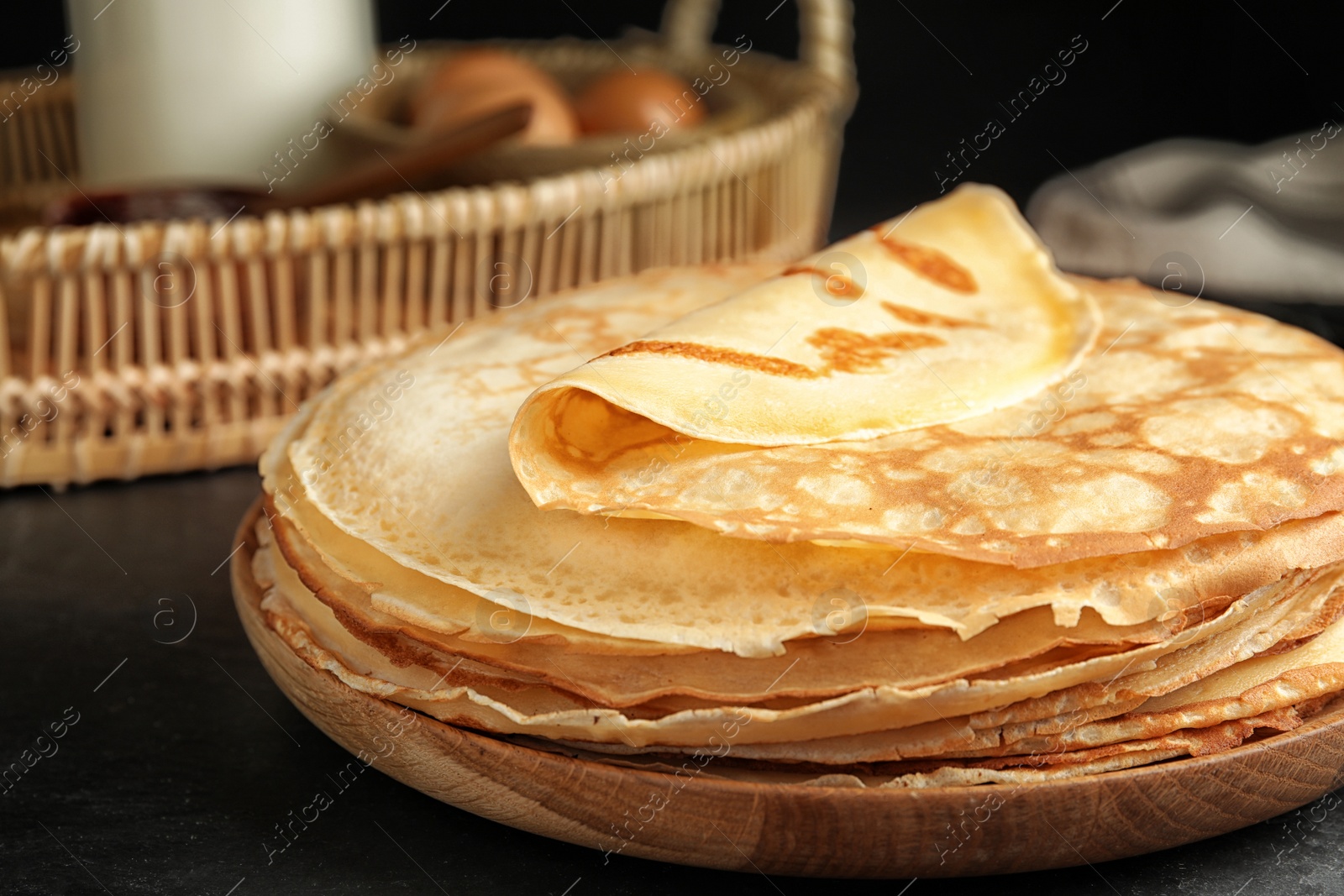 Photo of Stack of fresh thin pancakes on black table, closeup