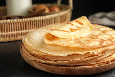 Photo of Stack of fresh thin pancakes on black table, closeup
