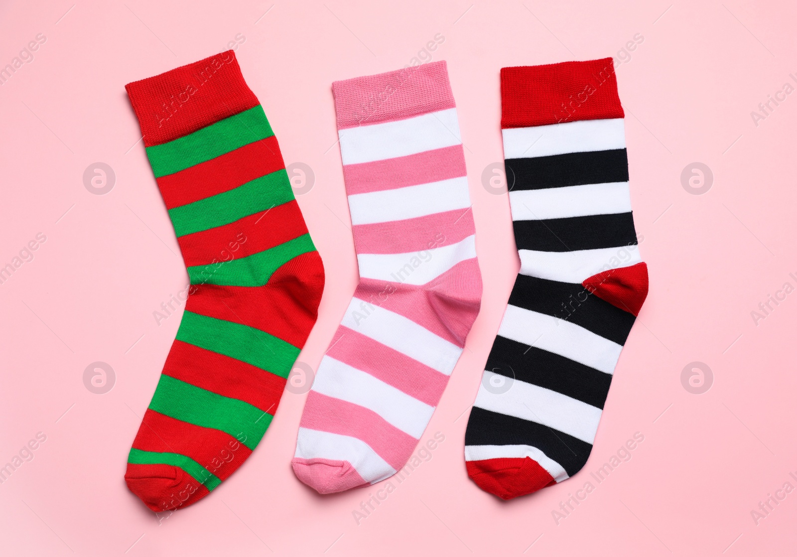 Photo of Different striped socks on light pink background, flat lay