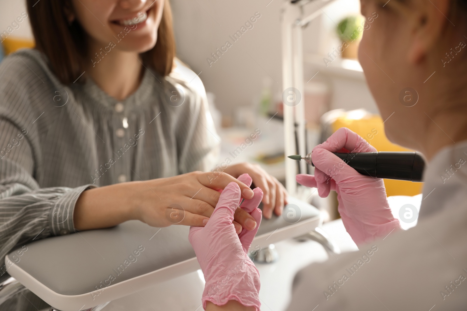 Photo of Professional manicurist working with client in beauty salon, closeup