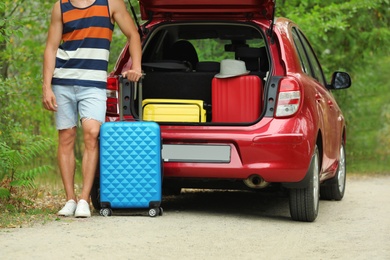 Man with suitcase near car trunk outdoors, closeup