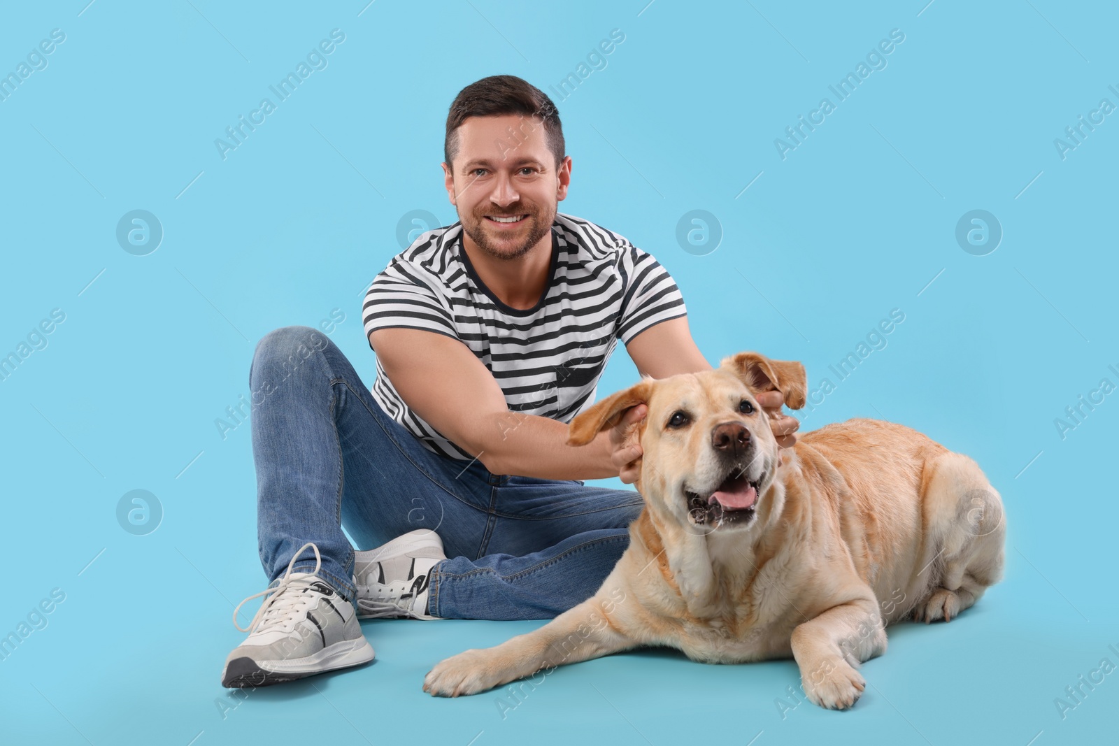 Photo of Man with adorable Labrador Retriever dog on light blue background. Lovely pet