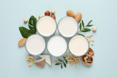 Vegan milk and different nuts on light background, flat lay
