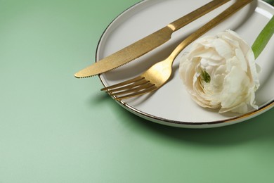 Photo of Stylish table setting with cutlery and flower on olive background, closeup. Space for text
