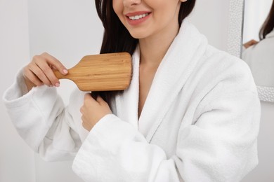 Beautiful woman brushing her hair indoors, closeup