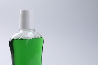 Photo of Fresh mouthwash in bottle on grey background, closeup. Space for text