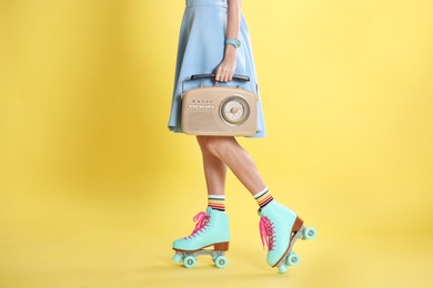 Photo of Young woman with roller skates and retro radio on color background, closeup
