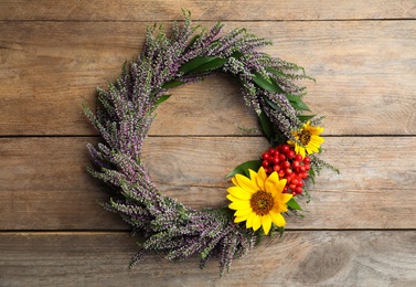 Photo of Beautiful autumnal wreath with heather flowers on wooden background, top view. Space for text