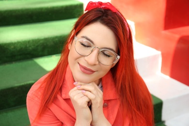 Photo of Young woman with bright dyed hair on stairs outdoors