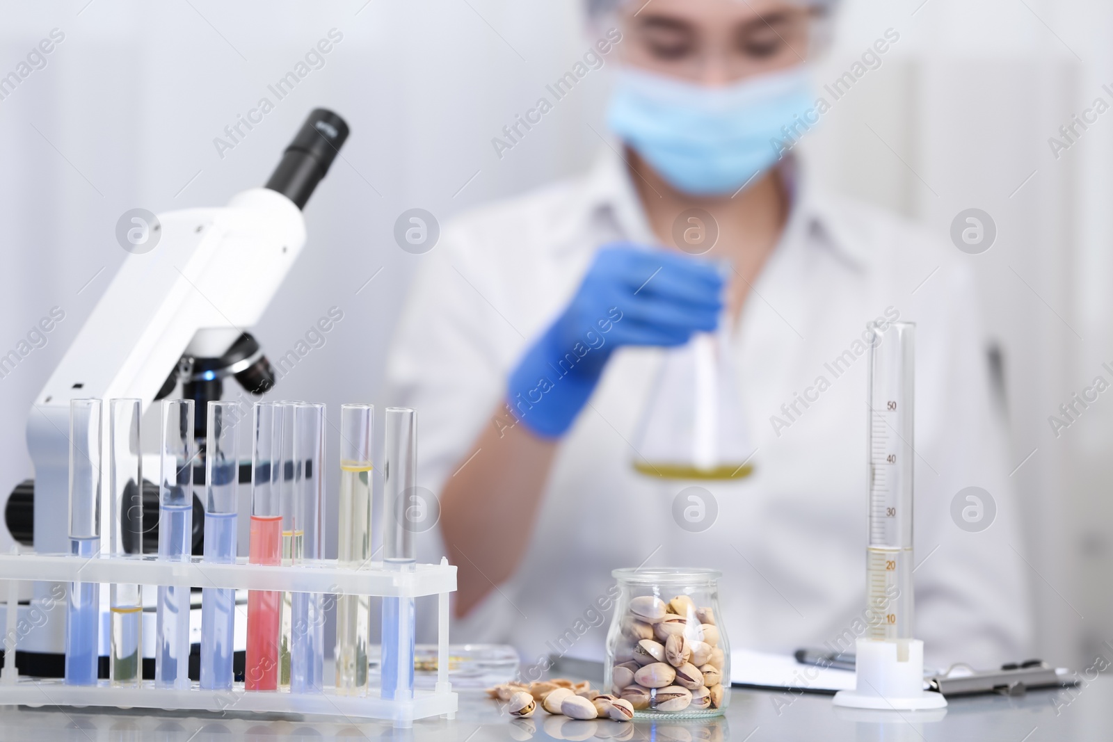 Photo of Pistachios on table and scientist proceeding quality control in laboratory