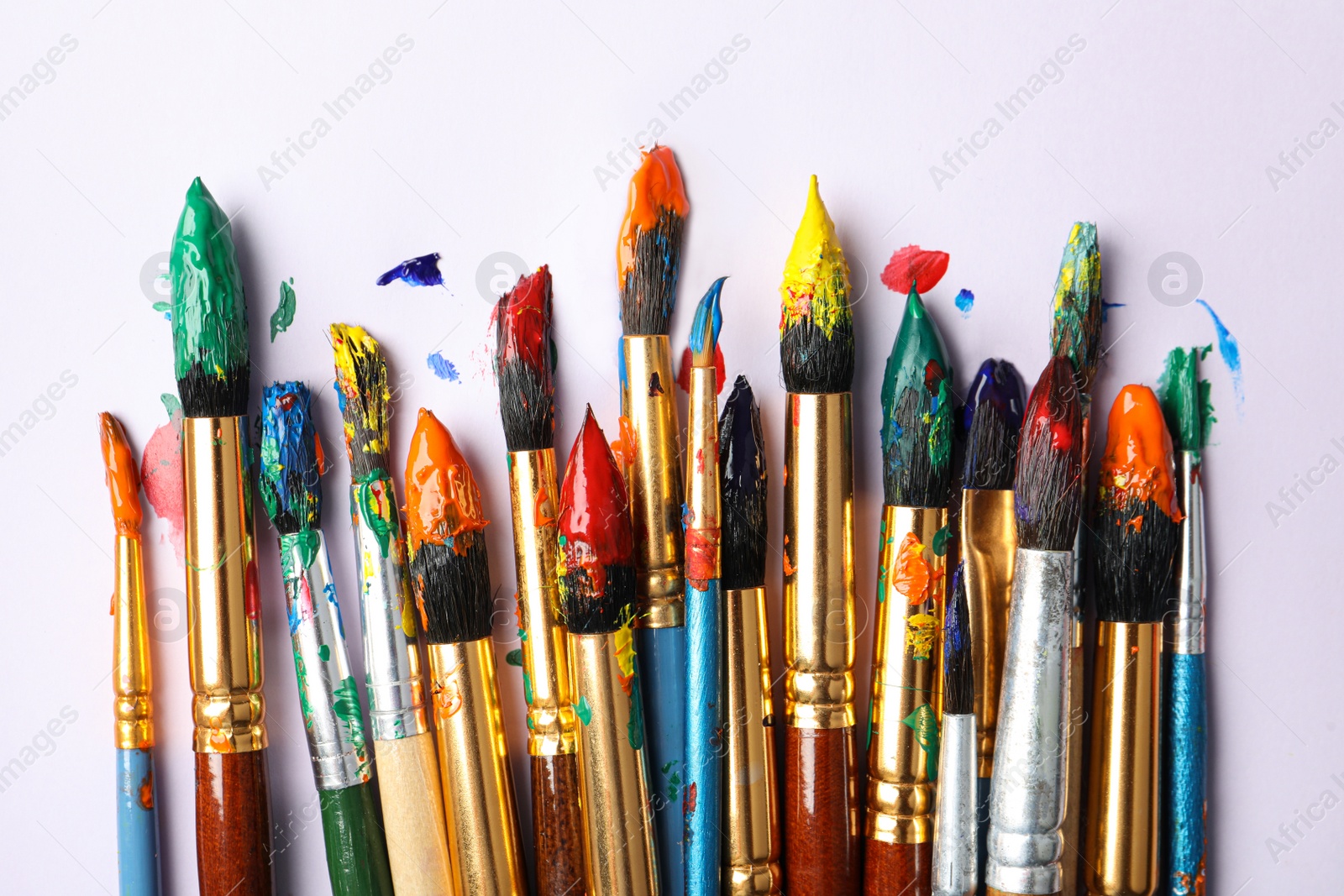 Photo of Brushes with colorful paints on white background, flat lay