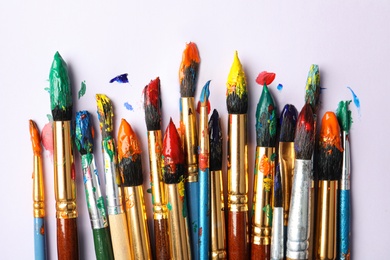 Photo of Brushes with colorful paints on white background, flat lay