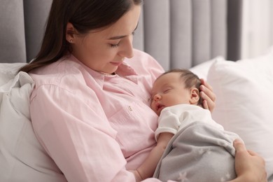 Mother with her sleeping newborn baby in bed