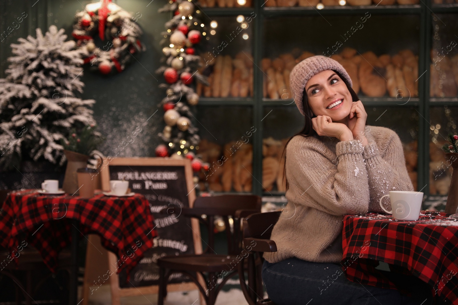 Photo of Beautiful woman at table in decorated cafe. Christmas celebration