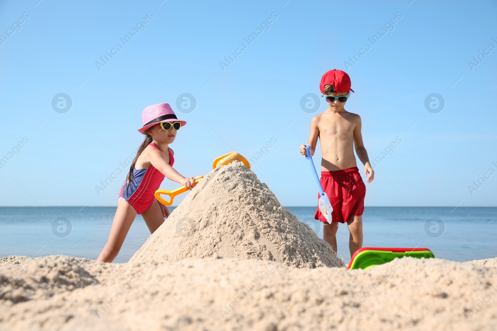 Photo of Cute little children playing with plastic toys on sandy beach