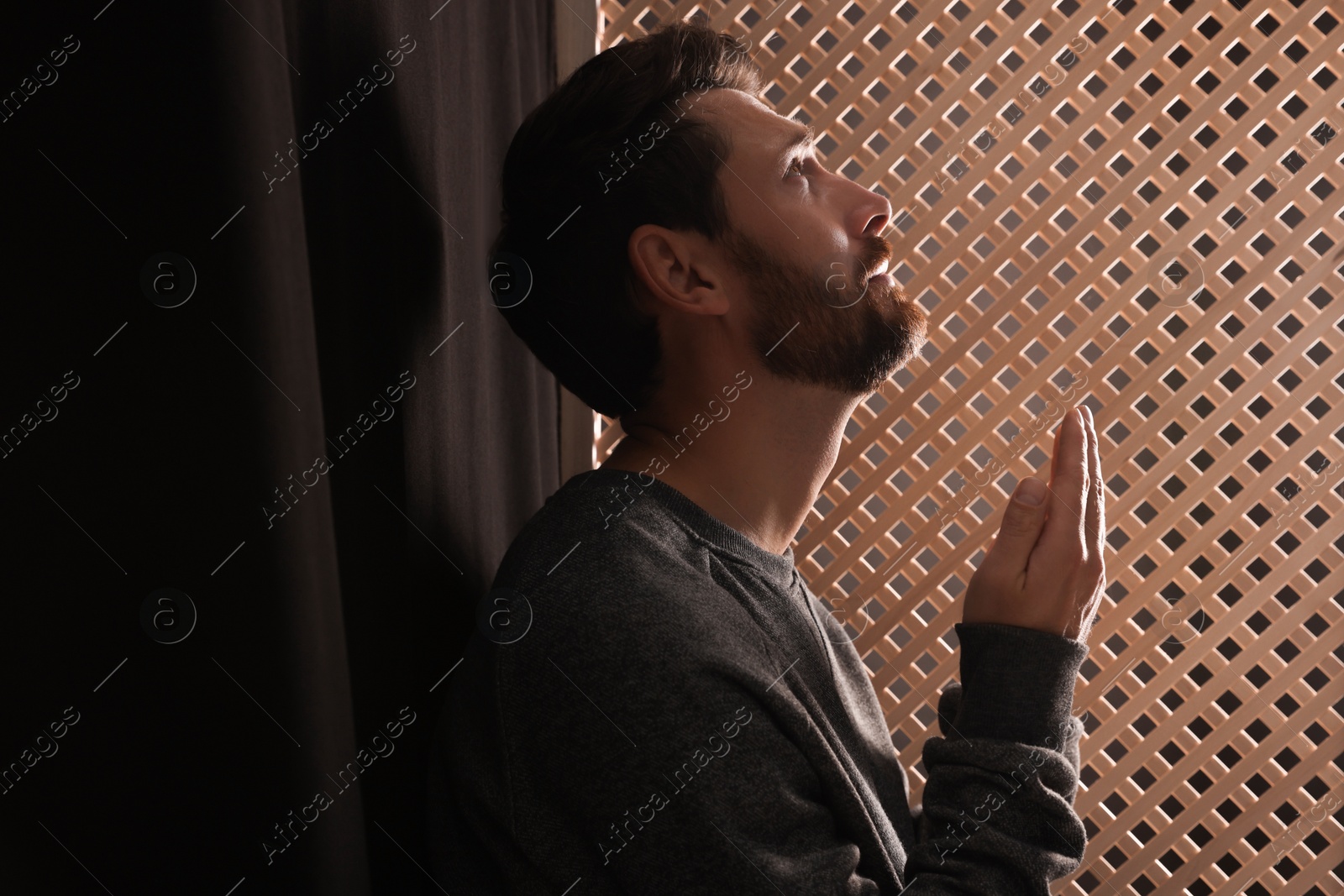 Photo of Man praying to God during confession in booth