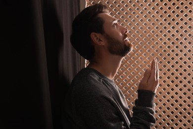 Man praying to God during confession in booth