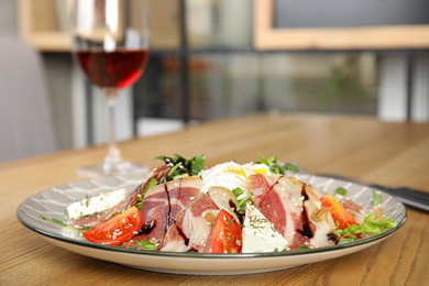 Photo of Delicious prosciutto salad with vegetables served on wooden table indoors. Space for text