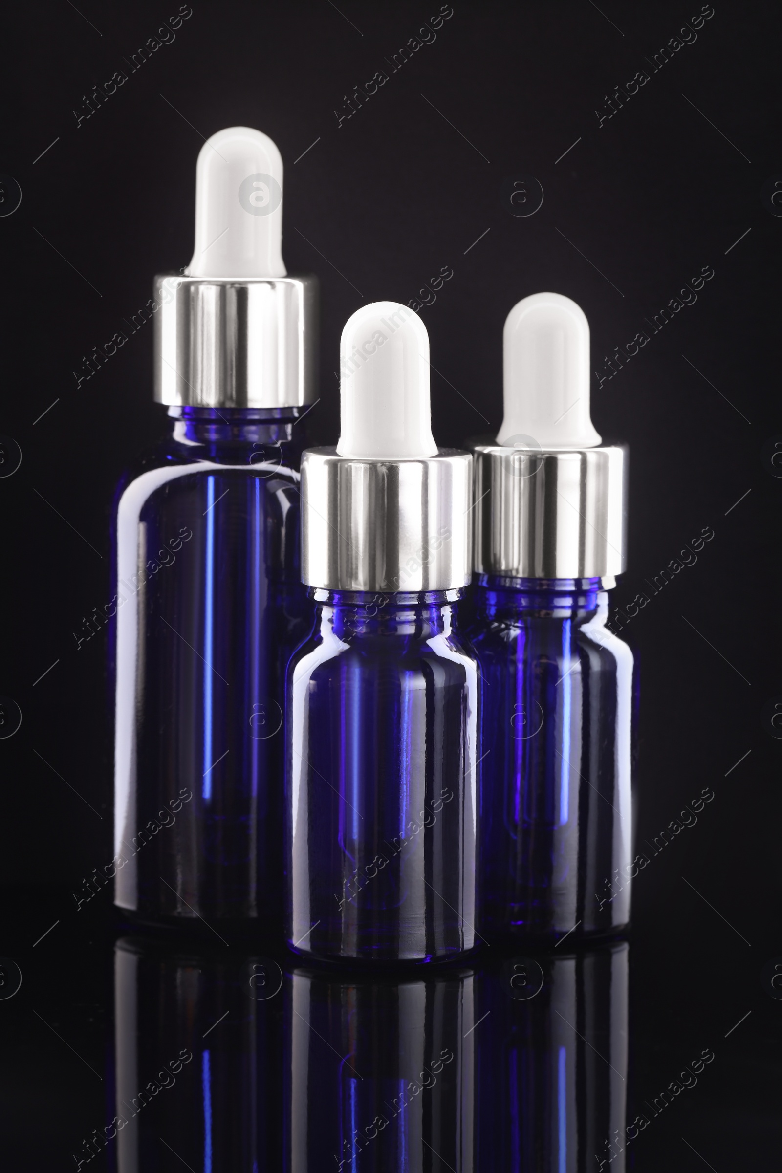 Photo of Tincture in bottles on mirror table against dark background