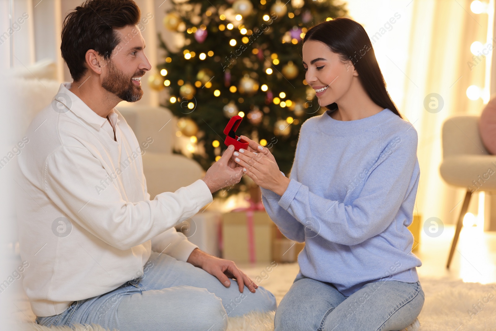 Photo of Man with engagement ring making proposal to his girlfriend at home on Christmas