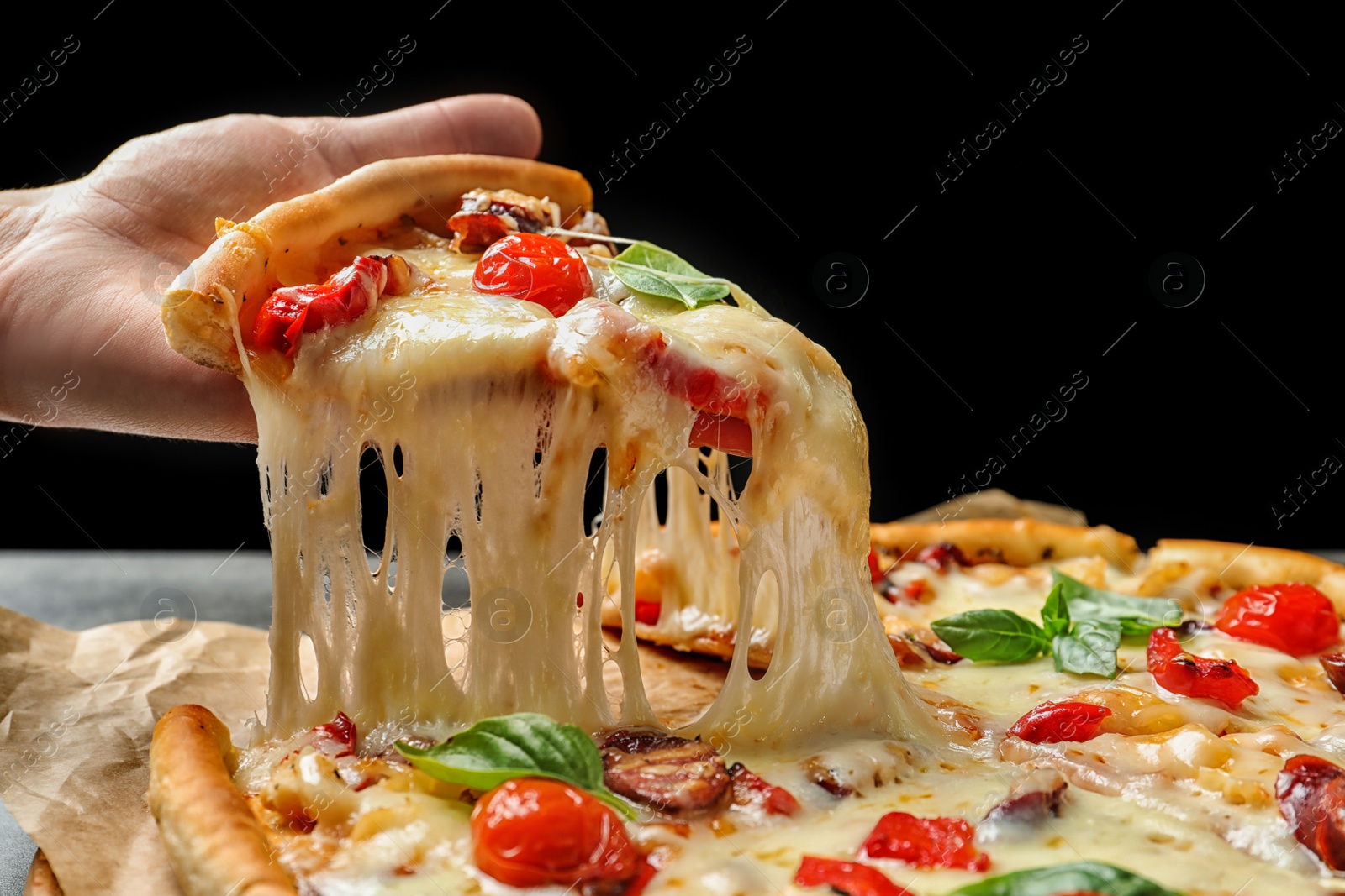 Photo of Woman holding slice of delicious hot pizza over table, closeup