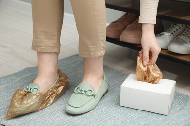 Woman wearing shoe covers onto her mules indoors, closeup