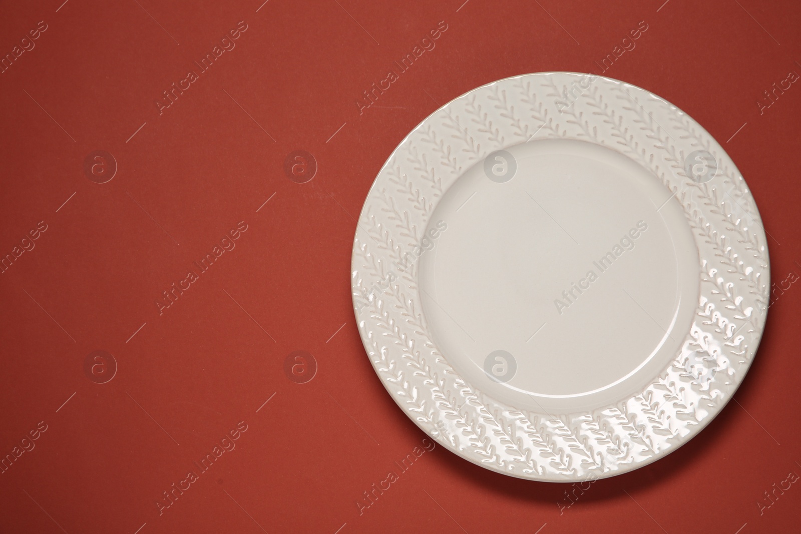 Photo of One white plate on red background, top view. Space for text