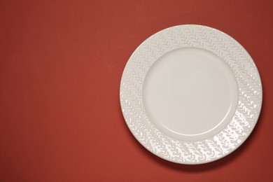 Photo of One white plate on red background, top view. Space for text