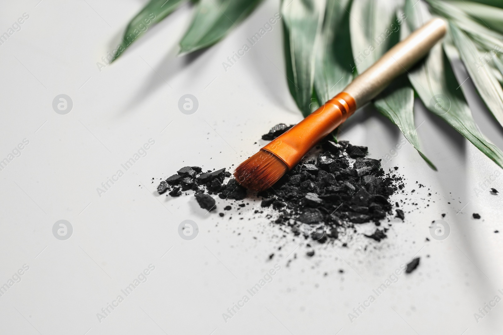 Photo of Makeup brush and crushed cosmetic product on white background