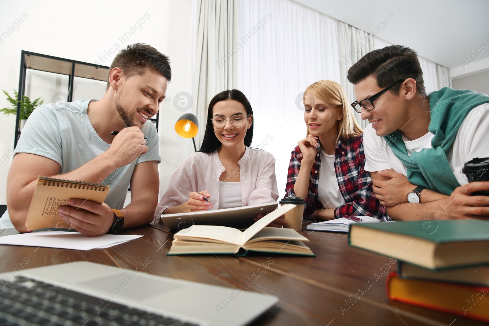 Photo of Young people discussing group project at table in library