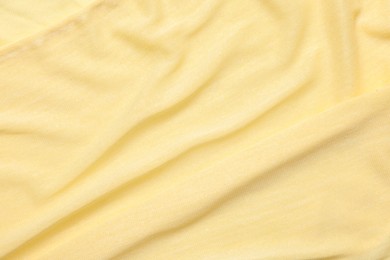 Texture of soft yellow crumpled fabric as background, top view