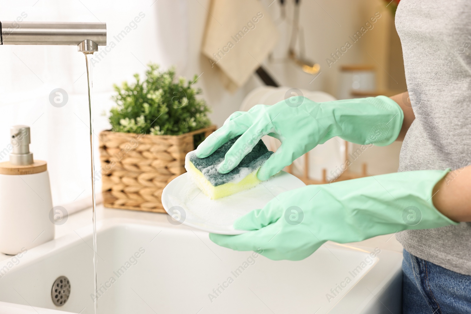 Photo of Woman washing dishes in kitchen sink, closeup. Cleaning chores