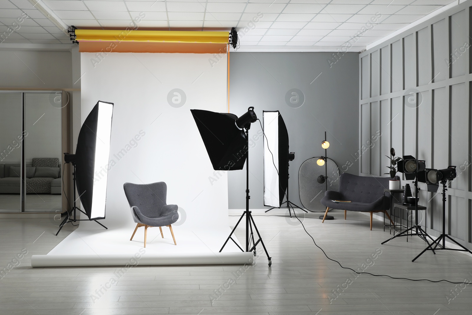 Photo of White photo background, armchair and professional lighting equipment in studio