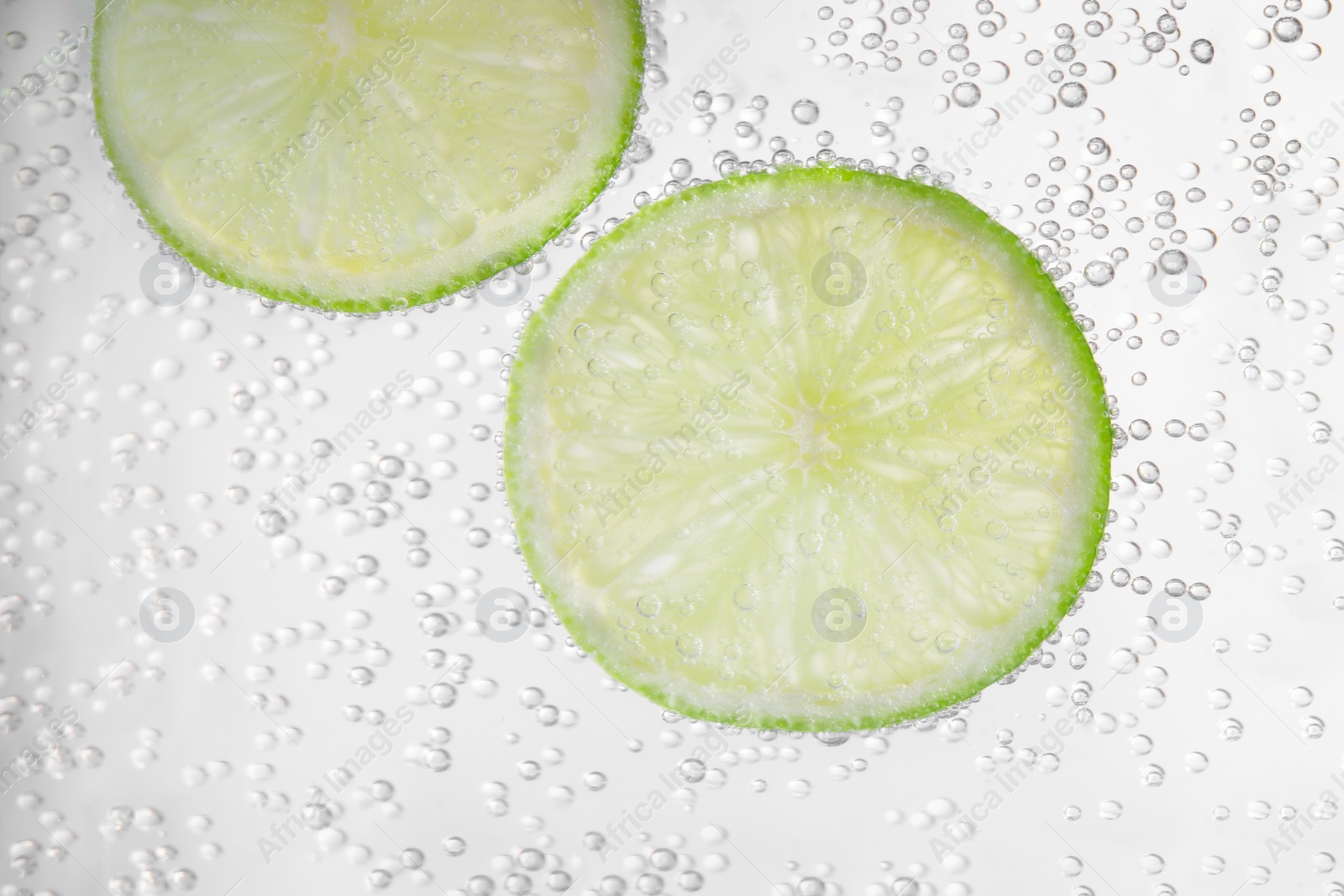 Photo of Juicy lime slices in soda water, closeup