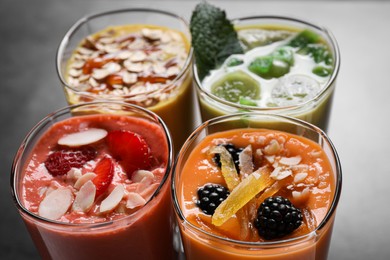 Photo of Many different delicious smoothies on grey table, closeup