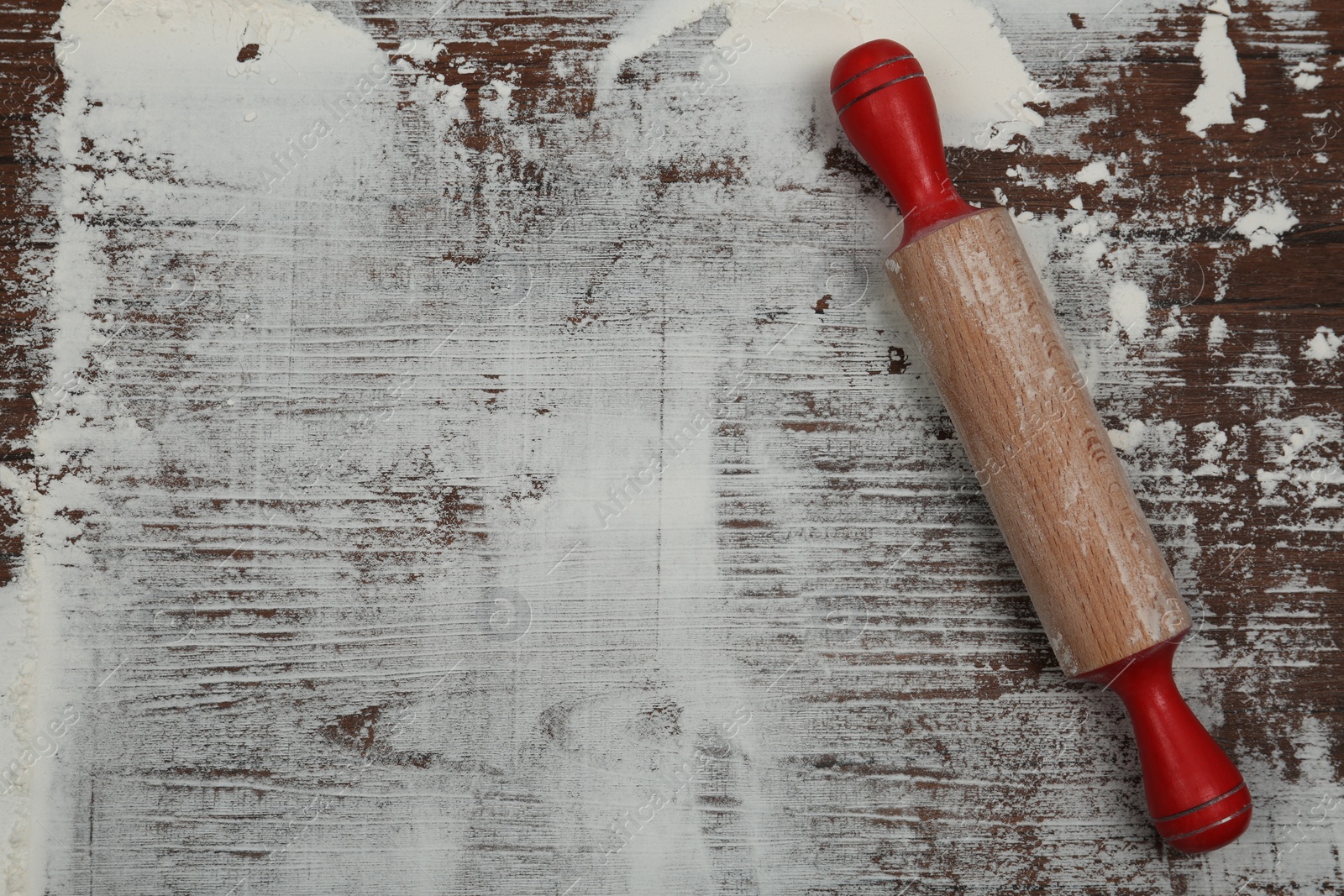 Photo of Flour and rolling pin on wooden table, top view. Space for text