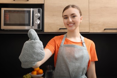 Photo of Beautiful young woman in clean apron at kitchen, focus on hand with oven glove