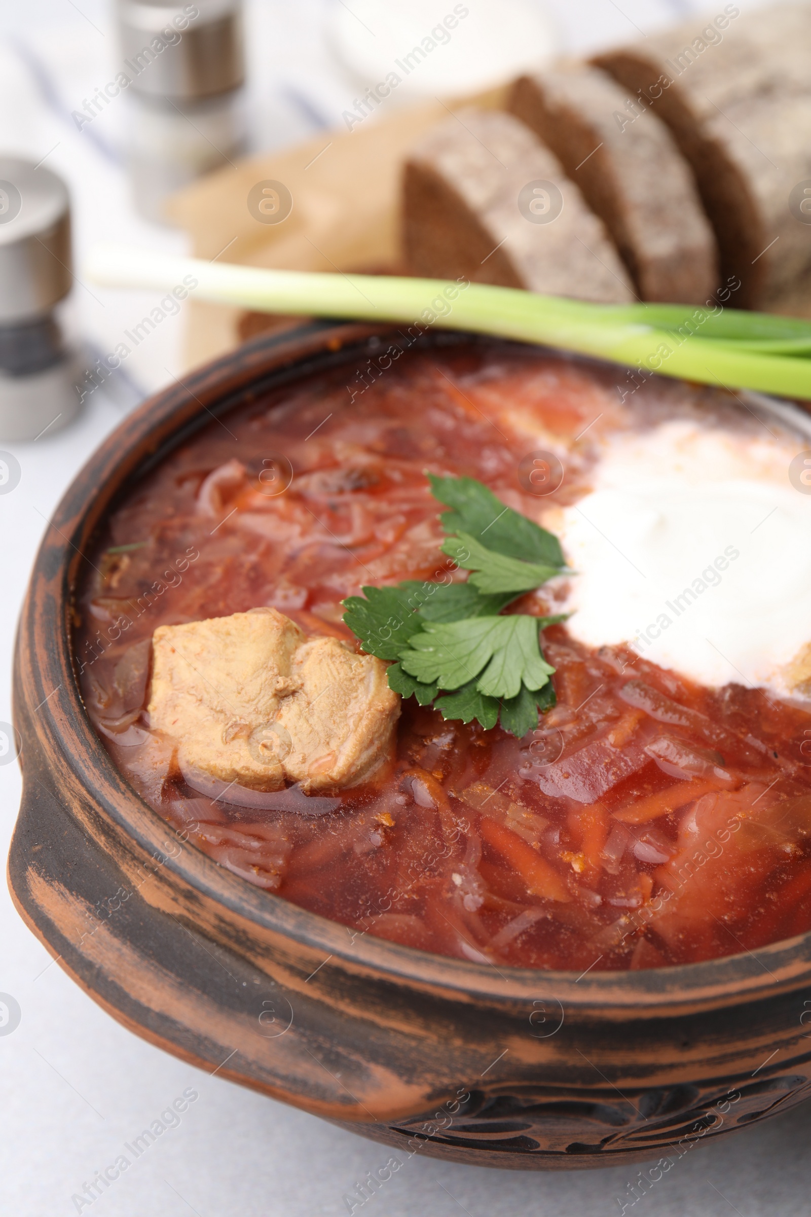 Photo of Tasty borscht with sour cream in bowl on light grey table, closeup